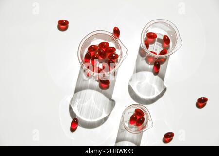 Capsules de gélatine d'huile de krill en flacons transparents de laboratoire sur fond blanc.acides gras oméga.Suppléments naturels.capsules volantes huile de krill rouge Banque D'Images