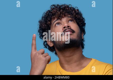 Homme concentré avec l'index relevé en regardant vers le plafond Banque D'Images