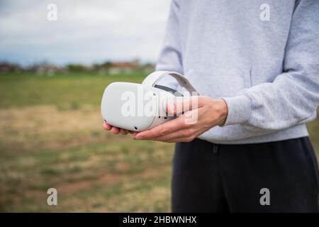 Gros plan des mains d'une personne tenant des micro-casques de réalité virtuelle.La réalité augmentée et le métaverse sont l'avenir.Concentrez-vous sur les micro-casques/oreillettes Banque D'Images