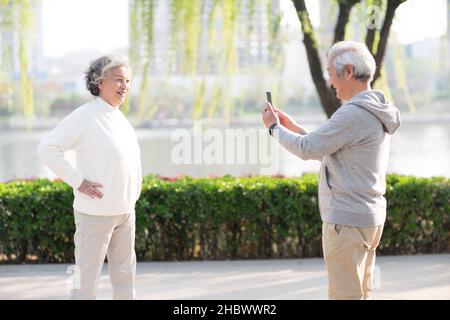 Homme âgé prenant des photos de sa femme avec son téléphone portable Banque D'Images