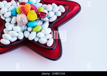 Bonbons traditionnels turcs durs, enrobés d'amande en forme d'étoile, plaque en verre rouge sur une surface blanche avec espace de copie Banque D'Images