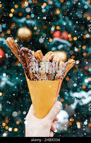 Gaufres churos dans la main sur le marché de la neige d'hiver.Churros cuisine mexicaine de rue dessert.Bonbons fast-food, biscuits de Noël.Photo de haute qualité Banque D'Images