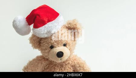 Cadeau de Noël.Ours en peluche portant chapeau de père Noël sur fond blanc, cadeaux de vacances pour enfants, jouets et animaux en peluche.Carte de vœux des fêtes. Banque D'Images