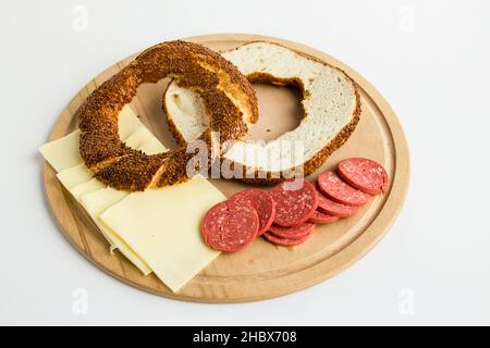 Préparez le bagel turc Simit coupé en deux sur l'assiette en bois avec du fromage et de la saucisse. Banque D'Images