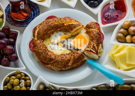 Petit-déjeuner turc traditionnel avec Bagel turc, simit, olives et thé. Tranché un morceau avec couteau bleu, au-dessus de la vue. Banque D'Images