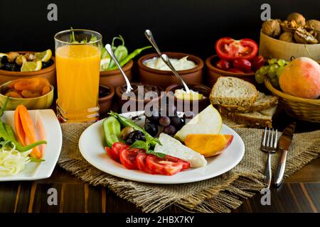 Petit déjeuner sans viande et Eggless avec fruits frais, fromage, olives, fruits secs, jus d'orange frais, pain de blé et légumes frais sur la table en bois Banque D'Images