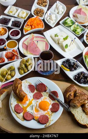 Traditionnel turc étendre petit déjeuner sur la table en bois.oeuf avec saucisse dans l'assiette blanche devant la table de petit déjeuner.image verticale. Banque D'Images