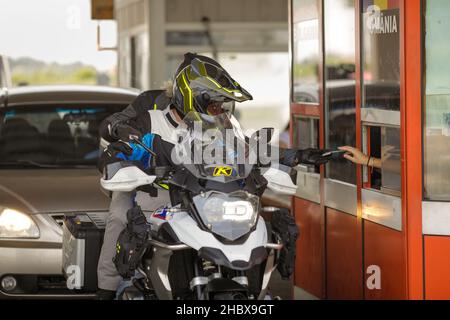 Giurgiu, Roumanie - 1 juillet 2021 : Rivière moto et passager montrent les documents de l'agent de police des frontières à la frontière terrestre et les douanes entre Bulgar Banque D'Images