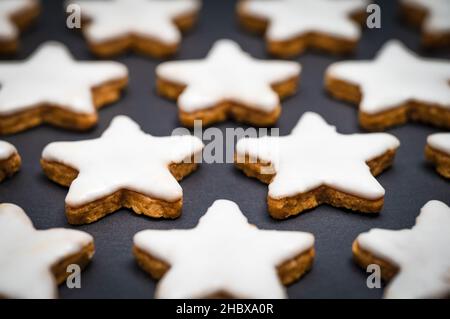 Étoiles de cannelle fraîchement cuites avec glaçage ou glaçage au sucre sur un fond d'ardoise noire. Banque D'Images