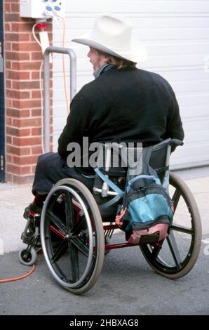 Homme attaché à un fauteuil roulant portant un chapeau de vache blanc attendant d'utiliser un ascenseur électrique pour entrer dans un bâtiment.Concept de vie autonome Banque D'Images