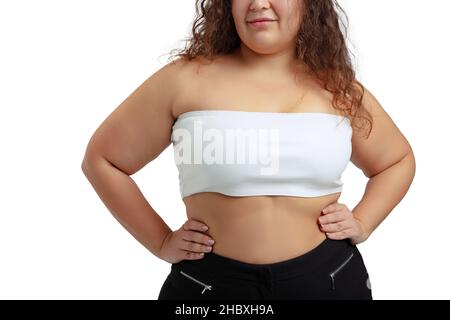 Image rognée d'une femme de taille plus vêtue d'un haut blanc et d'un Jean posé isolé sur un arrière-plan de studio blanc. Banque D'Images