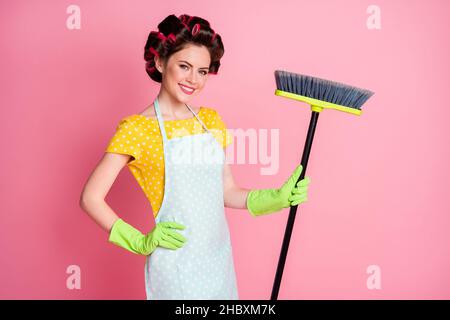 Portrait d'une femme de ménage très gaie et expérimentée effectuant un nettoyage soigné, isolé sur fond rose pastel Banque D'Images