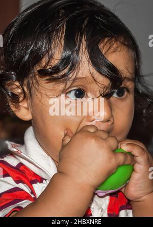 Un bébé indien de l'est montrant des signes de dentition en mâchant sur un jouet de dentition ou un anneau de dentition. Banque D'Images