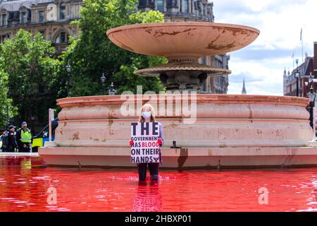 Animal rébellion protestant debout dans l'eau rouge dans la fontaine de Trafalgar Square tenant le sang d'écriteau sur les mains Banque D'Images