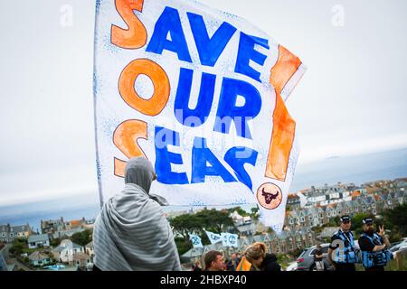 Rébellion animale protestante tenant un grand drapeau Save Our Seas surplombant la Cornouailles à G7 protestataires le 2021 juin Banque D'Images