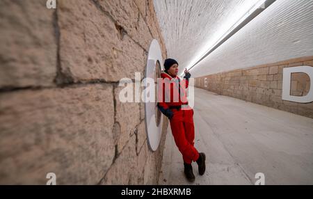 22 décembre 2021, Saxe, Chemnitz : l'artiste Anke Neumann se trouve dans le nouveau tunnel piétonnier de la gare centrale de Chemnitz.Le tunnel étroit entre le centre-ville et le quartier de Sonnenberg est en cours de modernisation, entre autres, par un nouveau concept d'éclairage.En outre, des lettres blanches de 1,40 mètres de haut sur les murs forment une citation de la chanson 'Wie ich' du groupe Kraftklub: 'ICH wär'gern weniger wie ich, ein bisschen mehr so wie du'.Dans le vernaculaire, le sous-passage de 220 mètres de long, auparavant plutôt sombre, est communément appelé le « tube germinatif ».En deux phases de construction, l'entra Banque D'Images