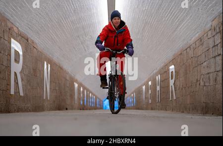 22 décembre 2021, Saxe, Chemnitz: L'artiste Anke Neumann conduit son vélo dans le nouveau tunnel piétonnier de la gare centrale de Chemnitz.Le tunnel étroit entre le centre-ville et le quartier de Sonnenberg est en cours de modernisation, entre autres, par un nouveau concept d'éclairage.En outre, des lettres blanches de 1,40 mètres de haut sur les murs forment une citation de la chanson 'Wie ich' du groupe Kraftklub: 'ICH wär'gern weniger wie ich, ein bisschen mehr so wie du' ('je voudrais être moins comme moi, un peu plus comme vous').Dans le vernaculaire, le passage inférieur de 220 mètres de long, auparavant plutôt sombre, est connu par le peuple Banque D'Images