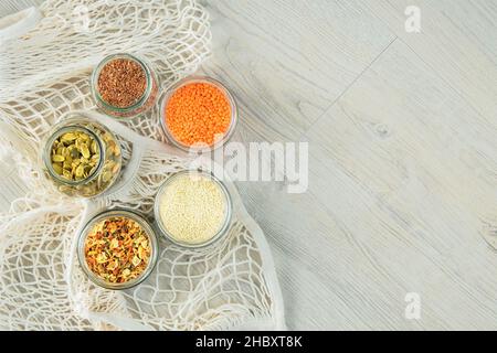 Graines de lin et de citrouille, graines de sésame, lentilles et légumes secs dans des pots en verre sur fond de bois.Les aliments biologiques dans zéro magasin de déchets.Copier l'espace. Banque D'Images