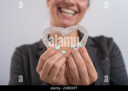 Femme caucasienne tenant deux aligneurs transparents en forme de cœur Banque D'Images