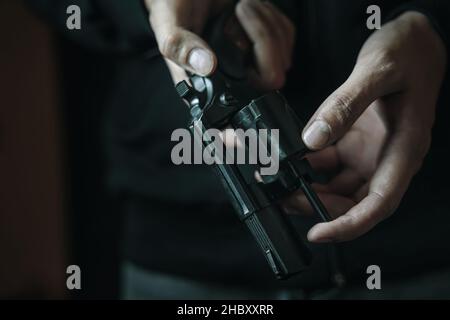 Les mains des hommes vérifient la présence de balles dans le corps du revolver. Banque D'Images