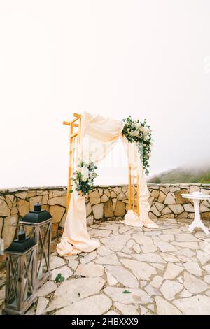 Arche de mariage décorée de fleurs et de supports en tissu sur des pavés Banque D'Images