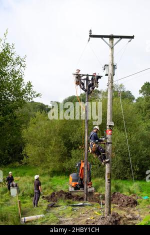 Travailleurs de l'énergie remplaçant l'ancien poteau de service public et connectant les câbles d'équipement de lignes électriques sur la propriété rurale au pays de Galles Grande-Bretagne KATHY DEWITT Banque D'Images