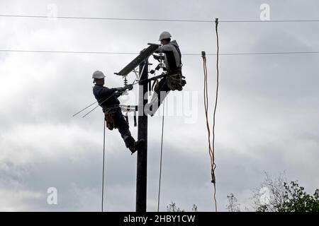 Travailleurs de l'énergie remplaçant l'ancien poteau de service public et connectant les câbles d'équipement de lignes électriques sur la propriété rurale au pays de Galles Royaume-Uni Grande-Bretagne 2021 Banque D'Images