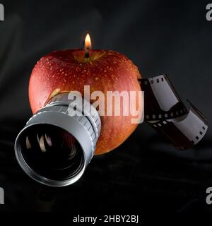 bougie pomme rouge avec lentille et rouleau de film, concept créatif Banque D'Images