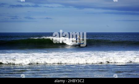 Pédalo surfant sur la crête d'une vague à la plage de Tynemouth long Sands Banque D'Images