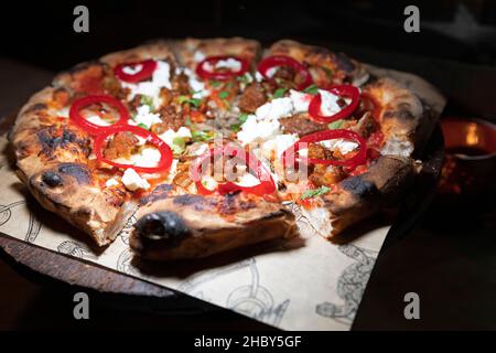 Pizza au levain recouverte de poivre rouge, de mozzarella et de poulet épicé.La pizza a été cuite dans un four à bois. Banque D'Images