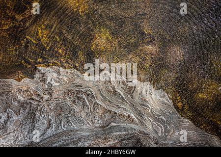 Vue de dessus de l'eau d'une rivière et d'une banque de rochers.Le vent donne à l'ensemble une texture superbe. Banque D'Images