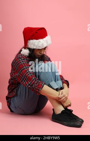 La femme asiatique avec chapeau de père noël debout sur fond rose. Banque D'Images