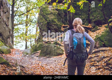 Randonnée en forêt.Femme avec randonneur à dos est debout entre les rochers dans les montagnes.Voyageur et nature d'automne. Banque D'Images