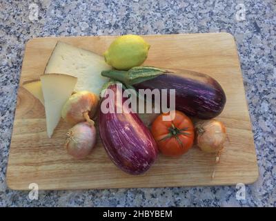 Aubergines rayées, tomates, oignons, citron et fromage sur une planche en bois, vue du dessus Banque D'Images