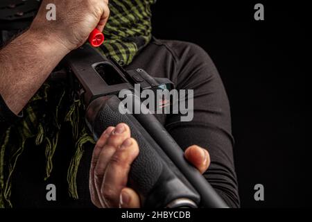 L'homme charge le fusil de chasse avec des munitions.Charger une arme Smoothbore à pompe.Gros plan. Banque D'Images