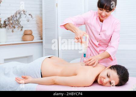 Une jeune femme détendue qui se détend sur le dos au spa est allongée sur une table de massage.Médecine alternative avec un physiothérapeute professionnel Banque D'Images