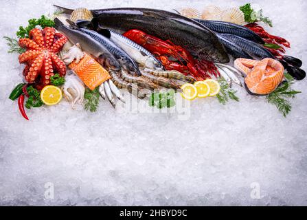 Matière première de fruits de mer avec vue sur la glace. Vue de dessus aliments méditerranéens congelés et herbes ingradent comme le citron, l'aneth, le persil. Banque D'Images