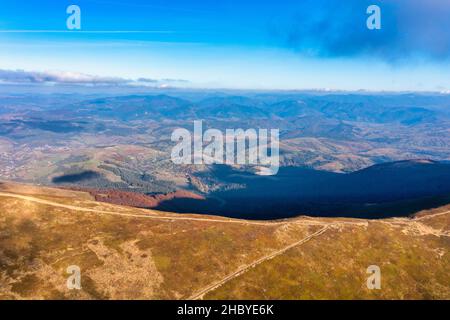 De longues allées étroites longeant la crête de haute montagne sous des nuages blancs moelleux flottant sur le ciel bleu sur une vue aérienne de jour ensoleillé Banque D'Images