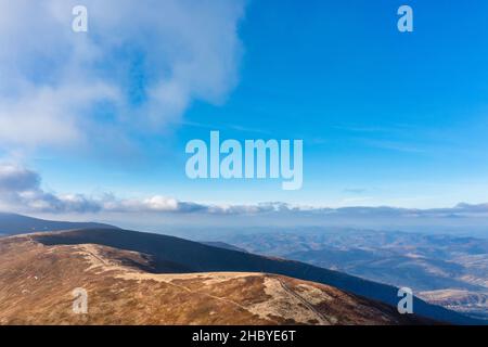 De longues allées étroites longeant la crête de haute montagne sous des nuages blancs moelleux flottant sur le ciel bleu sur une vue aérienne de jour ensoleillé Banque D'Images