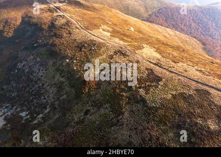 De longues allées étroites longeant la crête de haute montagne sous des nuages blancs moelleux flottant sur le ciel bleu sur une vue aérienne de jour ensoleillé Banque D'Images