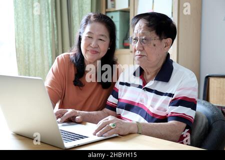 Le couple asiatique utilisant un ordinateur portable dans la maison. Banque D'Images