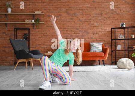 Petite fille rouge en t-shirt vert dansant à la maison Banque D'Images