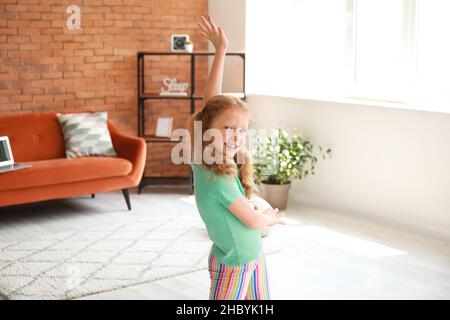 Petite fille rouge en t-shirt vert dansant à la maison Banque D'Images