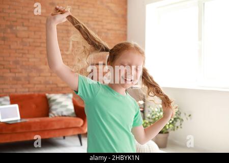 Petite fille rouge en t-shirt vert dansant à la maison Banque D'Images