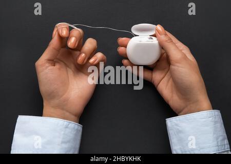 Femme avec soie dentaire sur fond noir Banque D'Images