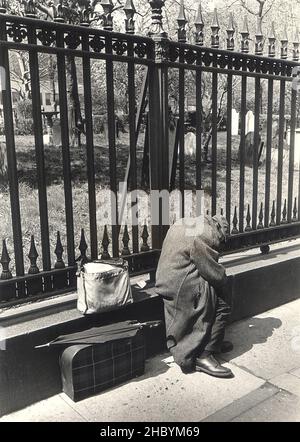 Sans-abri homme avec ses effets se trouve à l'extérieur de Trinity Church sur Lower Broadway à Manhattan, New York City. Banque D'Images