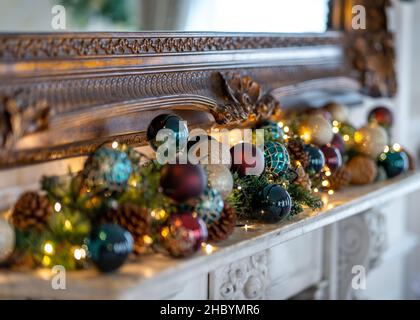 Belles décorations de Noël traditionnelles et lumières boules rouges branches de sapin de pin sur frieplace.Illuminé avec des lumières de Noël pour les fêtes de fin d'année Banque D'Images