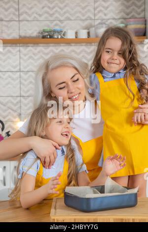 La maman caucasienne et deux filles goûtent les biscuits juste cuits ensemble Banque D'Images