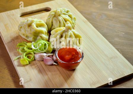 Boulettes de Khinkali à la sauce, prêtes à manger sur une planche de bois.Cuisine nationale géorgienne. Banque D'Images