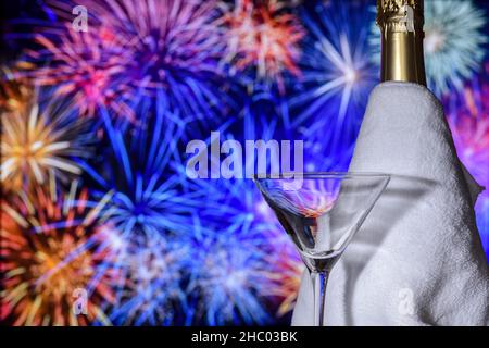 Verre de fête avec une bouteille de champagne sur fond de feux d'artifice flous lors de la célébration du nouvel an. Banque D'Images